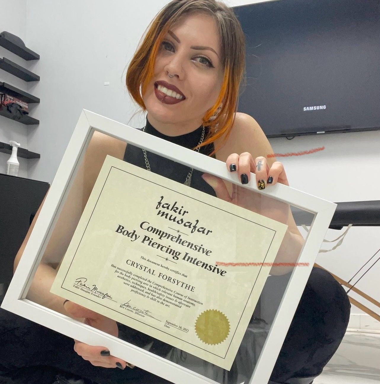 A woman is holding a certificate that says body piercing intensive