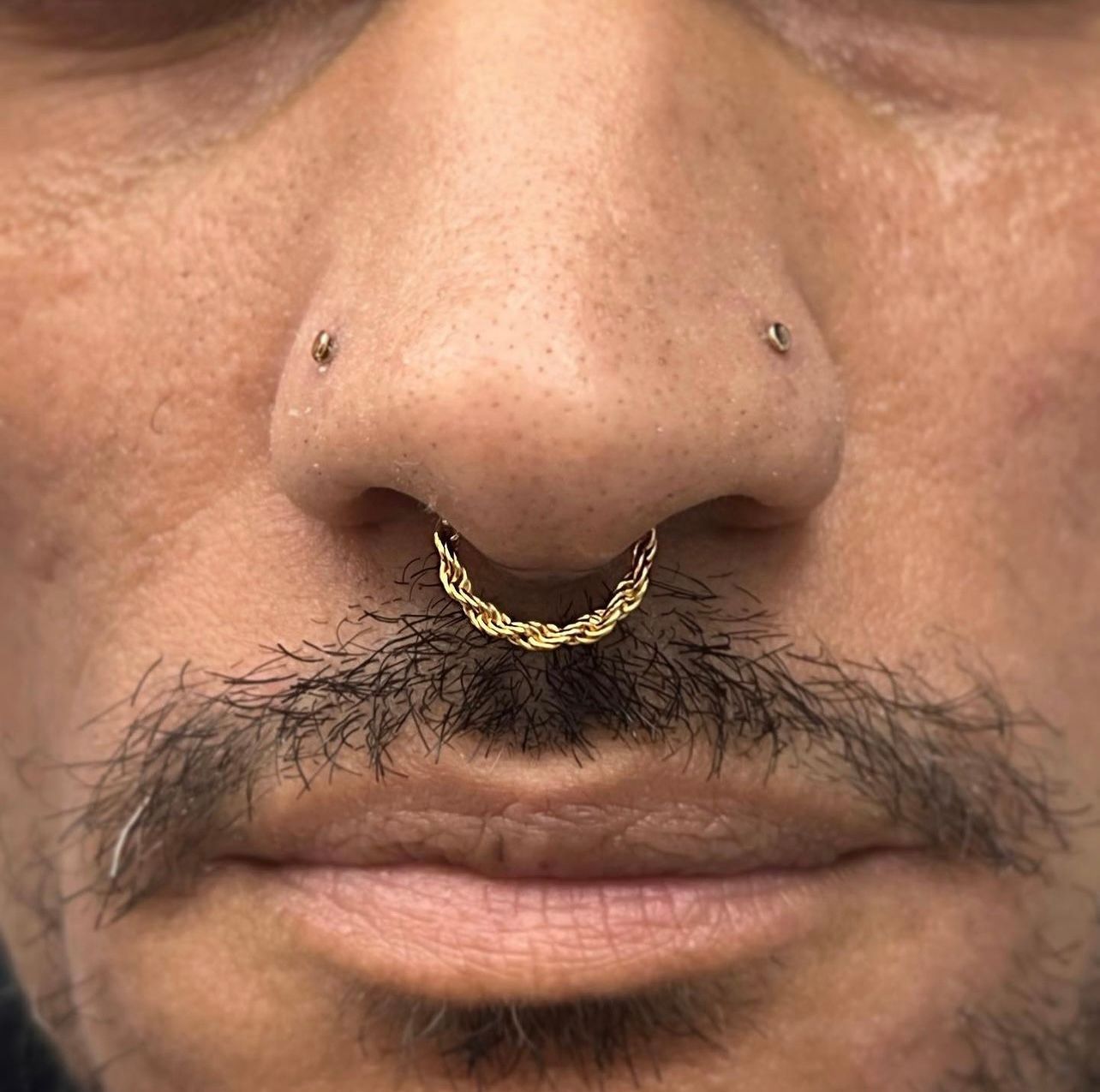 a close up of a man 's nose with a nose ring .