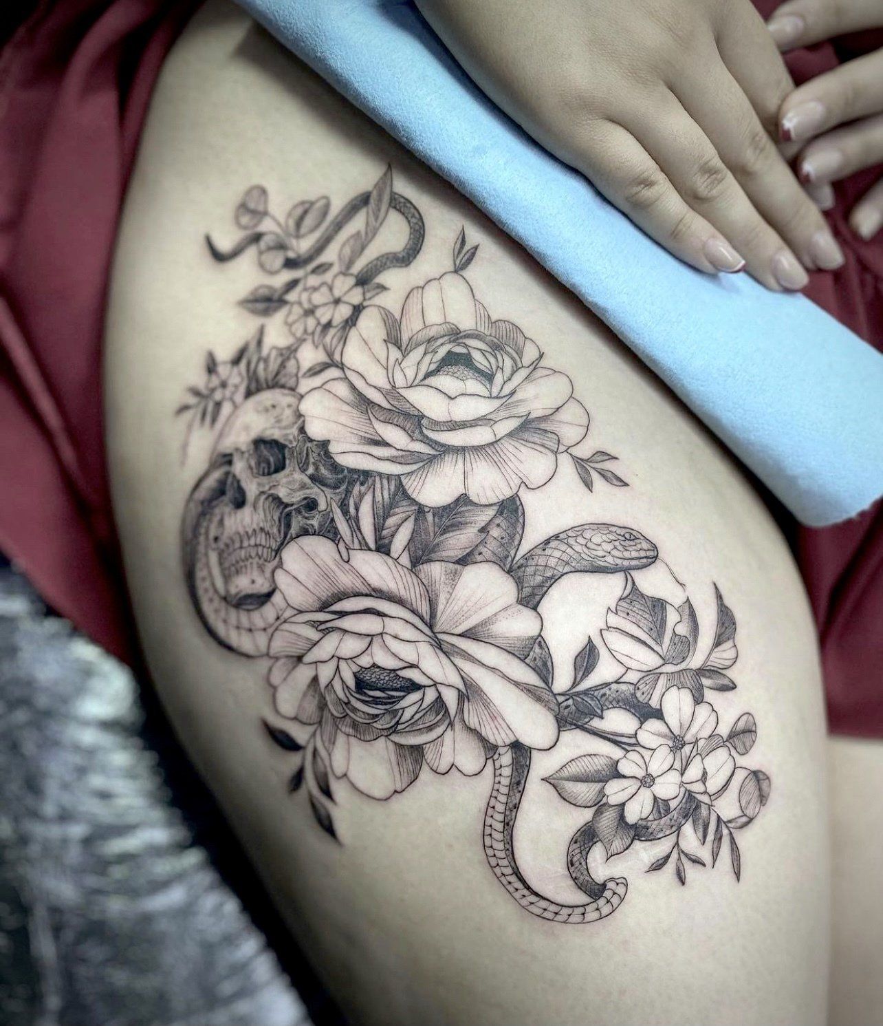 a woman has a tattoo of flowers and a snake on her thigh