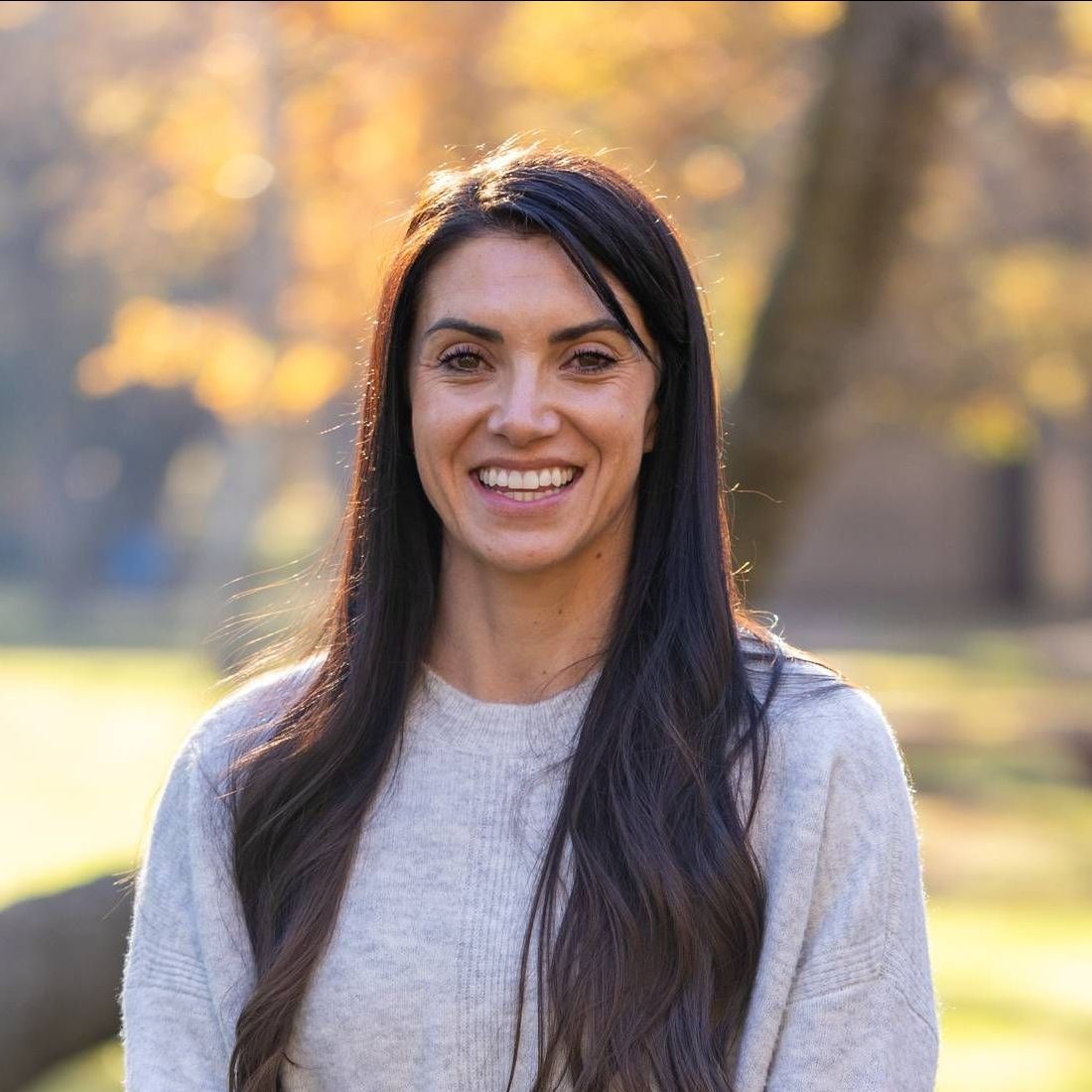 A man in a suit and tie is standing in front of a plant.
