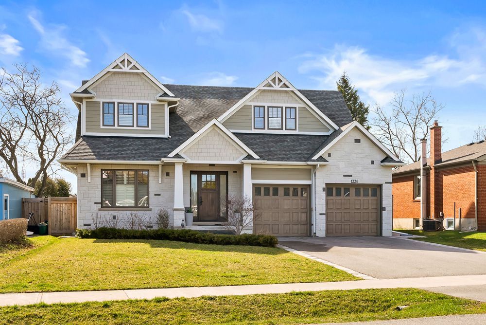 A large white house with two garages and a brick house in the background on Tansley Drive by Oakroots Construction