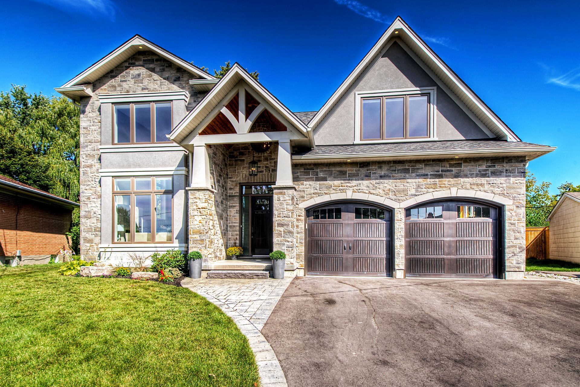 A large stone house with two garage doors and a driveway