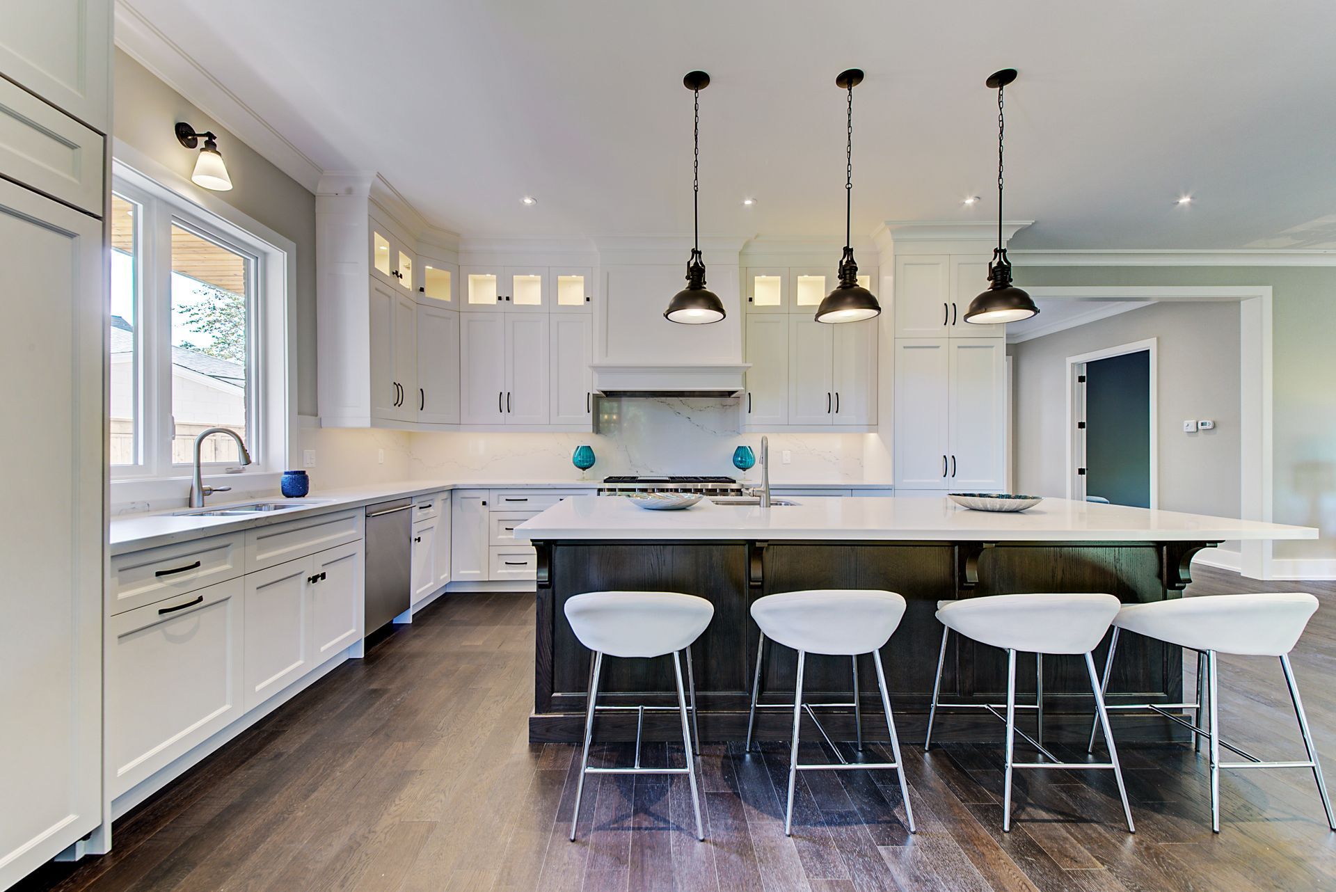 A kitchen with white cabinets and stools and a large island.