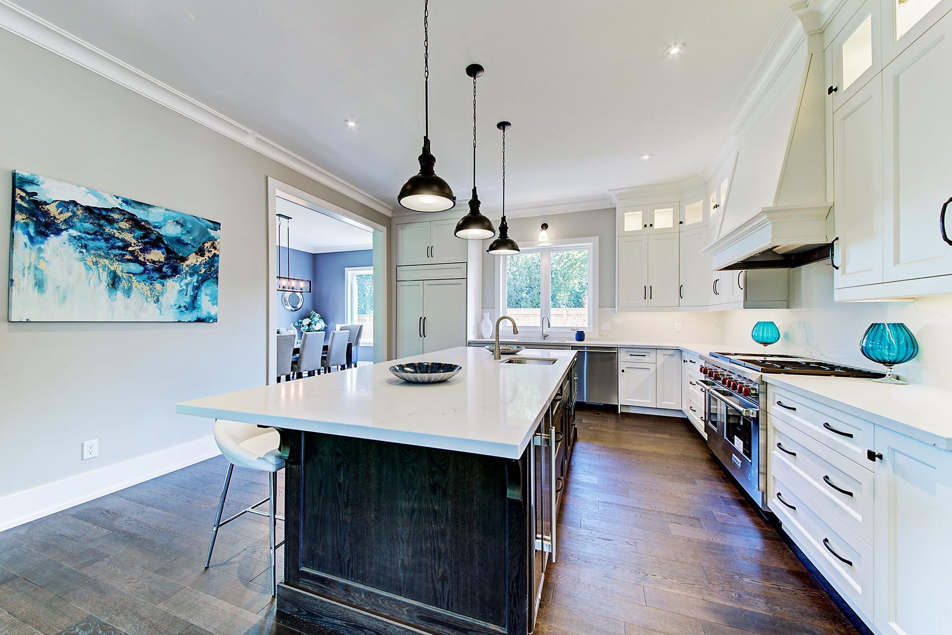 A kitchen with white cabinets and stainless steel appliances and a large island in the middle.