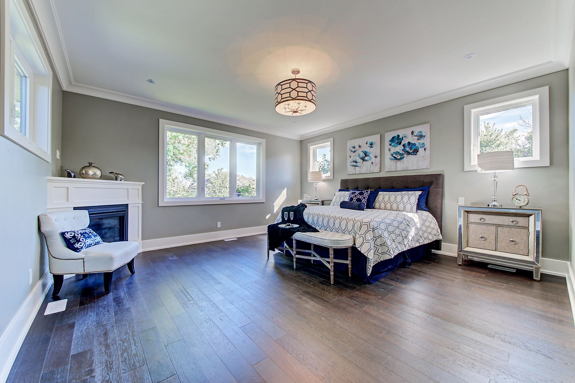 A large bedroom with a bed , chair , nightstand and fireplace.