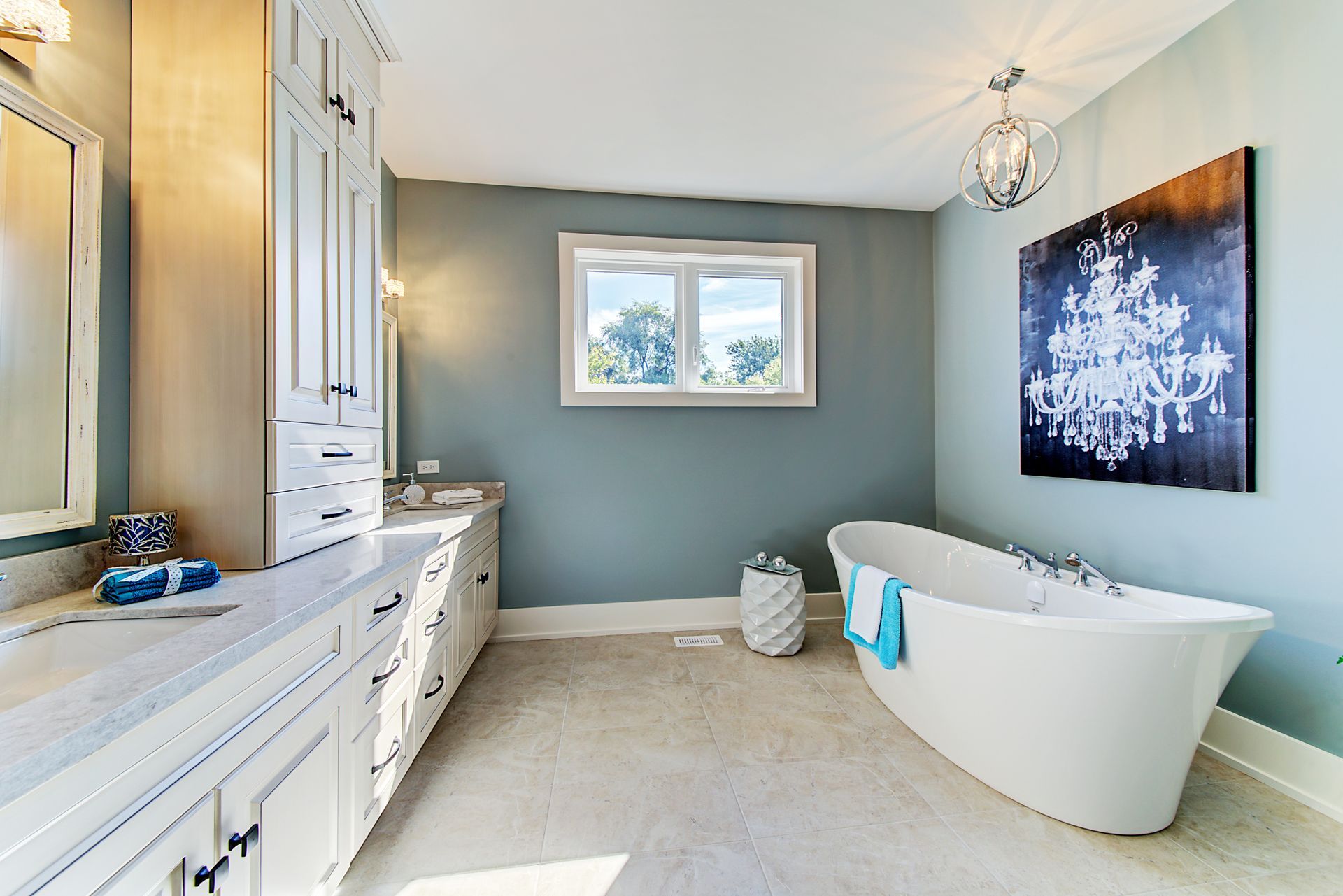 A bathroom with a tub , sink , mirror and window.