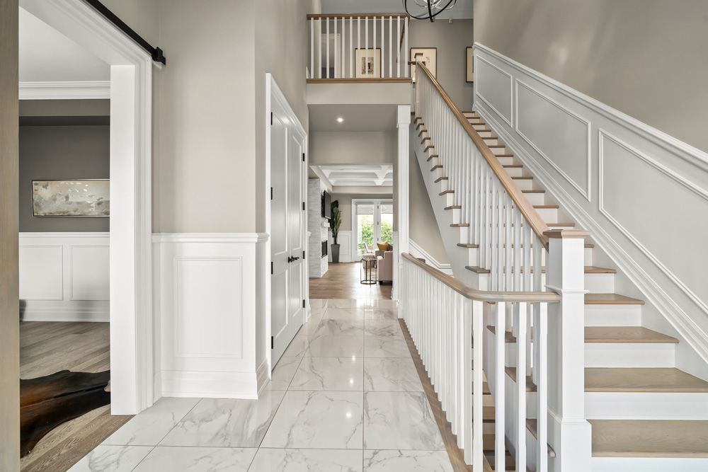 A hallway with stairs leading up to the second floor of a house in Tansley Drive by Oakroots Construction