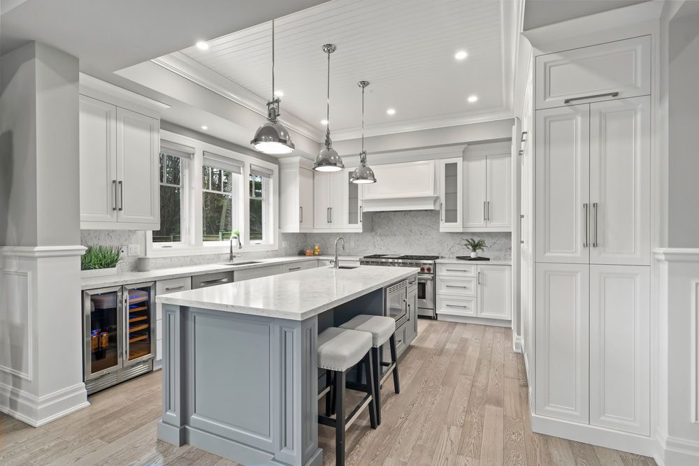 A kitchen with white cabinets, stainless steel appliances, and a large island on Tansley Drive by Oakroots Construction