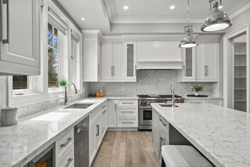 A kitchen with white cabinets, granite countertops, stainless steel appliances and a large island on Tansley Drive by Oakroots Construction