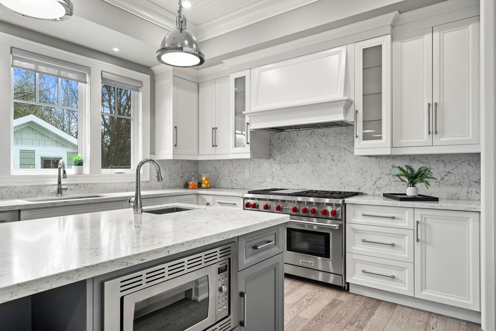 A kitchen with white cabinets, stainless steel appliances, and a large island on Tansley Drive by Oakroots Construction