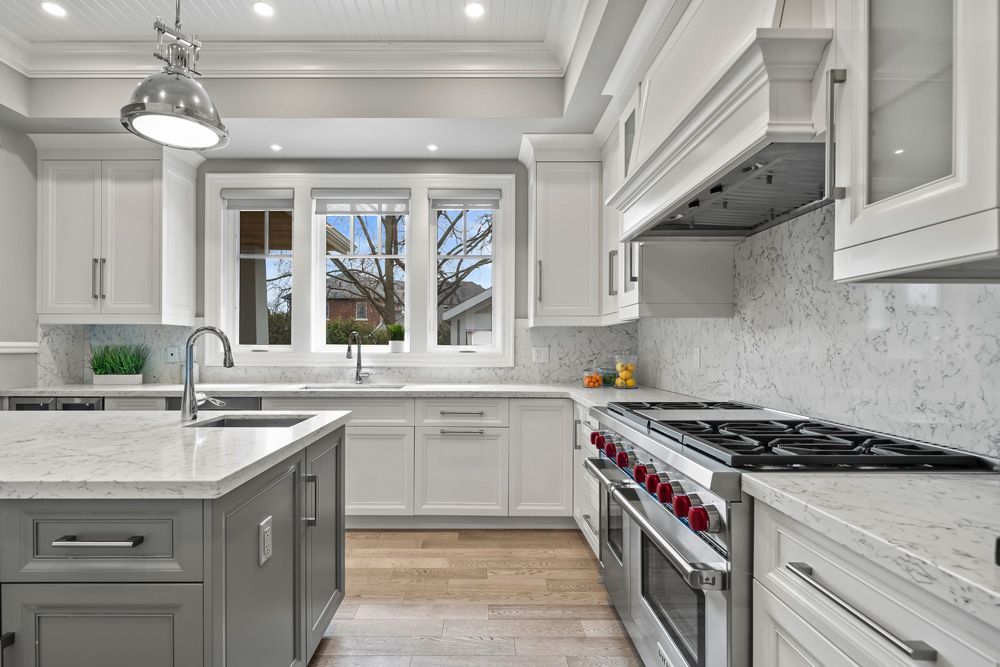 A kitchen with white cabinets, a stove, a sink, and a large island on Tansley Drive by Oakroots Construction