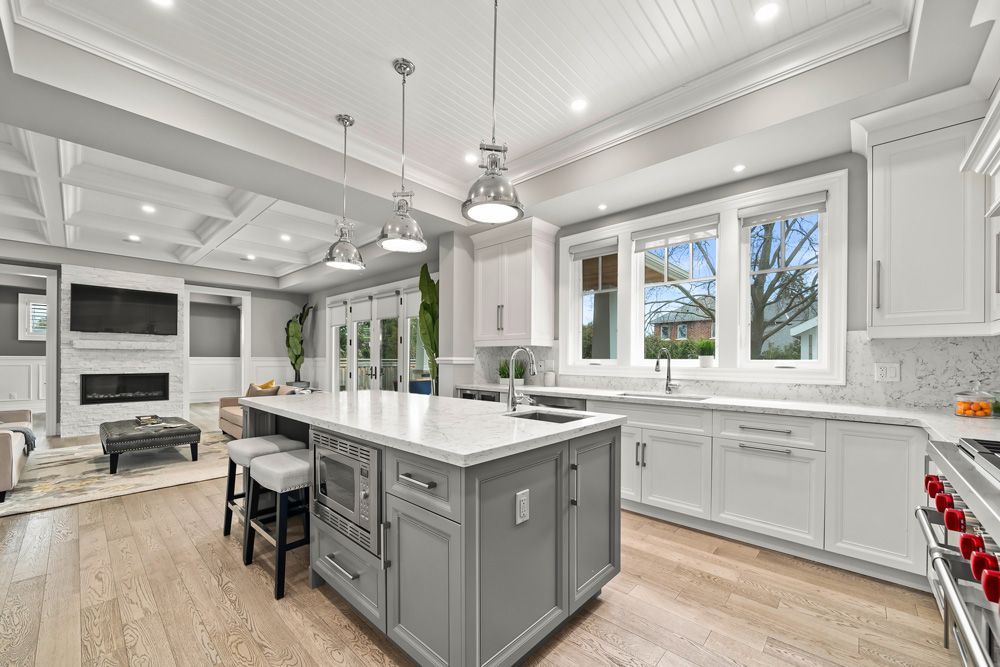 A kitchen with white cabinets and a large island in the middle on Tansley Drive by Oakroots Construction
