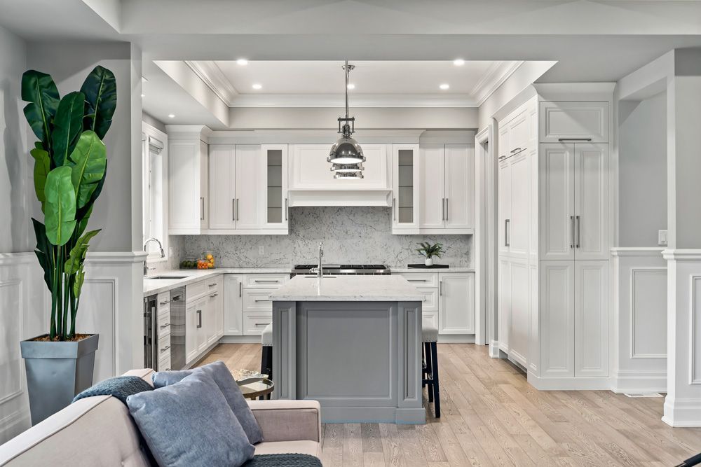 A kitchen with white cabinets and a large island in the middle of the room on Tansley Drive by Oakroots Construction