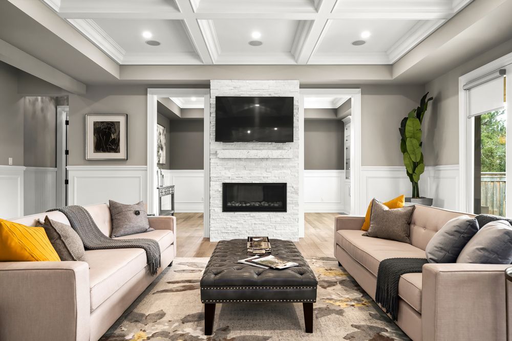 A living room with two couches, a coffee table, a fireplace and a flat-screen tv on Tansley Drive by Oakroots Construction