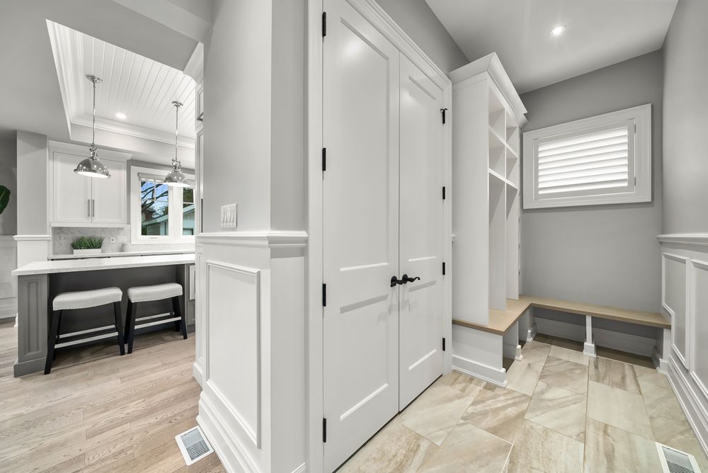 A hallway in a house with white cabinets and a bench on Tansley Drive by Oakroots Construction