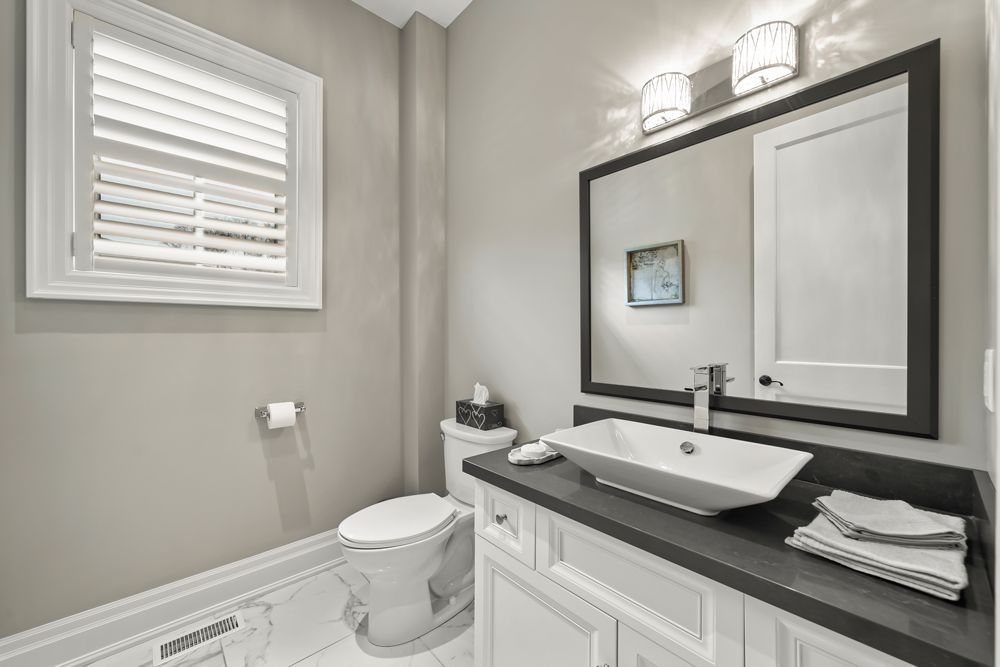A bathroom with a toilet , sink , mirror and window on Tansley Drive by Oakroots Construction