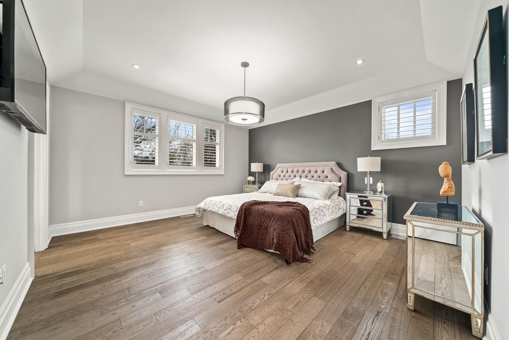 A bedroom with a large bed , nightstands , lamps and a flat screen tv on Tansley Drive by Oakroots Construction