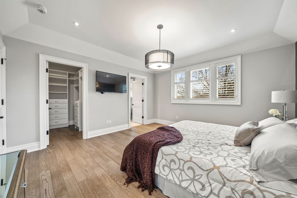 A bedroom with a large bed and a walk-in closet on Tansley Drive by Oakroots Construction