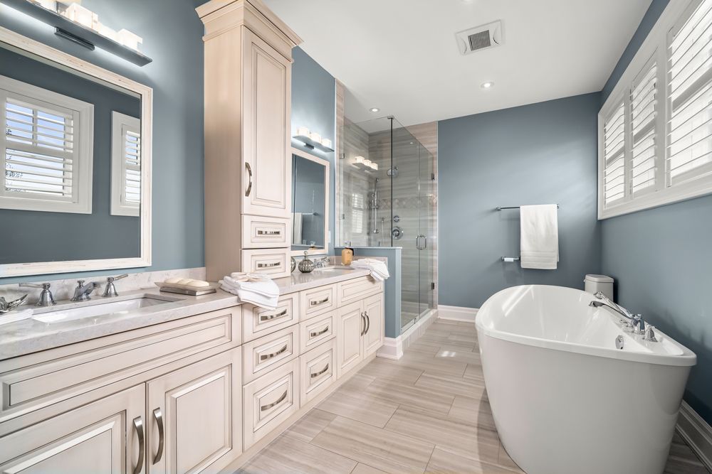 A bathroom with a tub, sinks, mirrors and shutters on Tansley Drive by Oakroots Construction