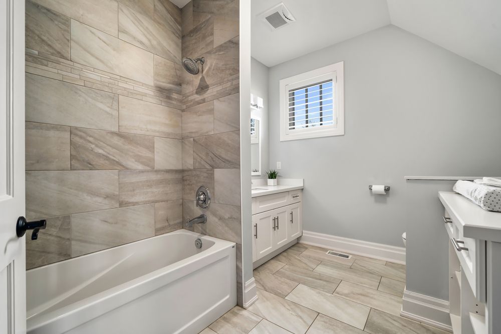 A bathroom with a tub, sink, and shower on Tansley Drive by Oakroots Construction