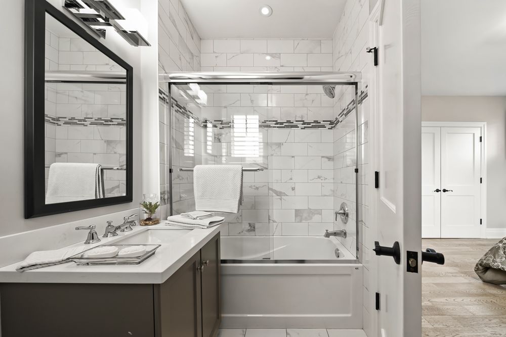 A bathroom with a tub, sink, mirror and shower on Tansley Drive by Oakroots Construction