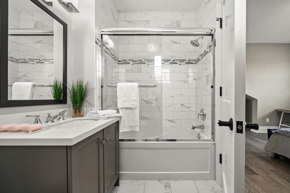 A bathroom with a sink, tub, shower and mirror on Tansley Drive by Oakroots Construction