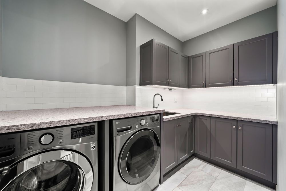 A laundry room with a washer and dryer and a sink on Tansley Drive by Oakroots Construction