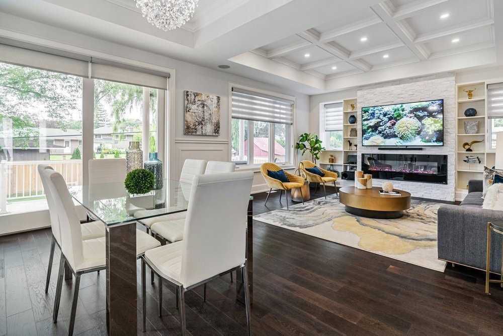 A living room with a dining table , chairs , a couch and a television.
