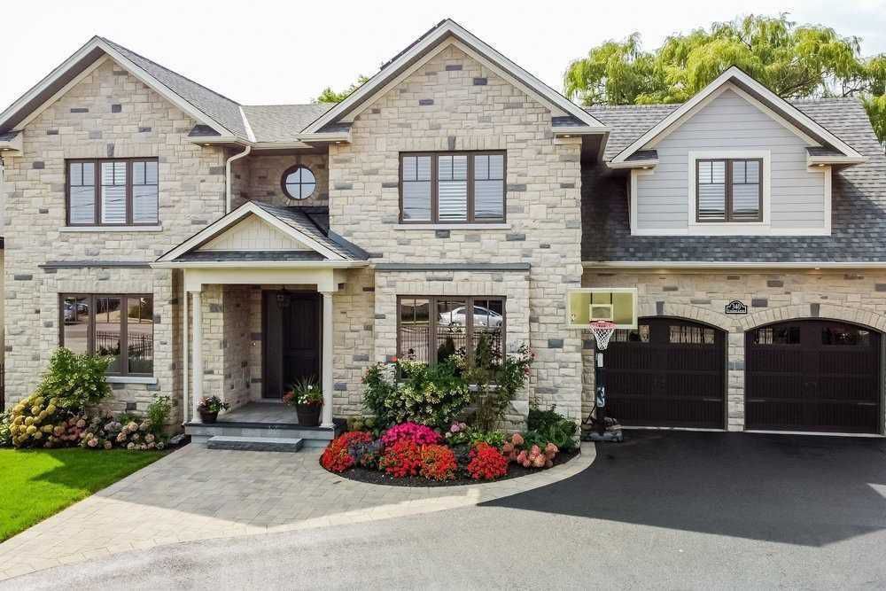 A large brick house with two garages and a basketball hoop in front of it.