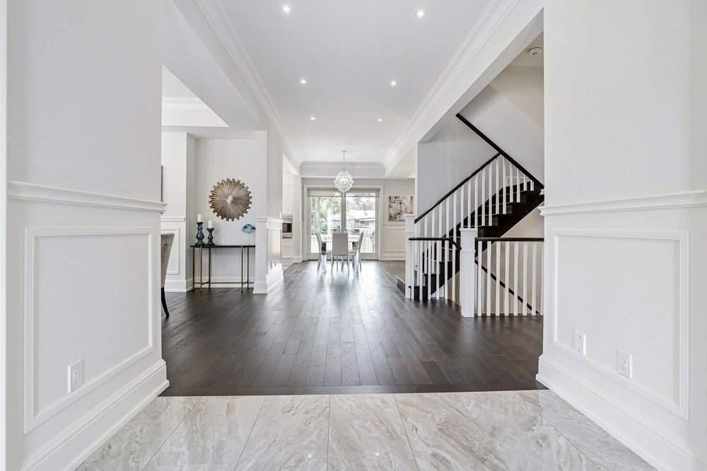 A hallway with hardwood floors and a staircase in a house.