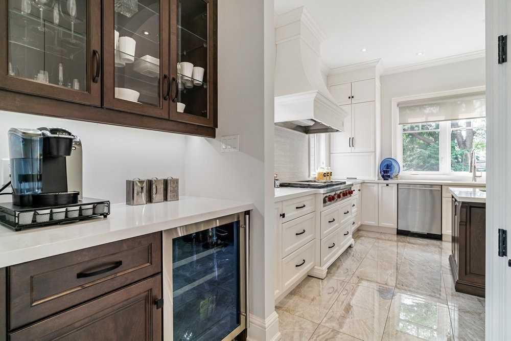 A kitchen with white cabinets , stainless steel appliances , a refrigerator and a coffee maker.