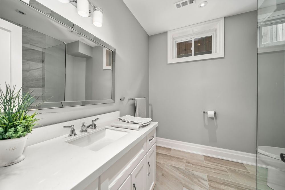 A bathroom with a sink , toilet and mirror on Tansley Drive by Oakroots Construction