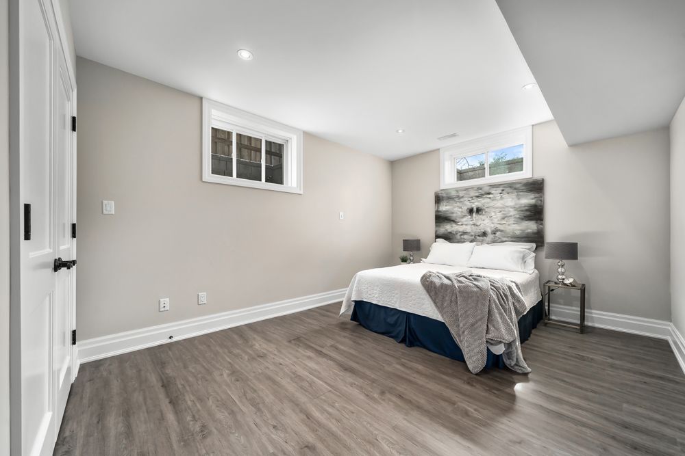 A bedroom in a basement with hardwood floors and a bed on Tansley Drive by Oakroots Construction