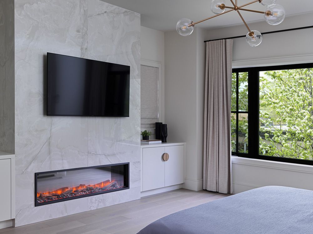 A bedroom with a fireplace and a flat-screen tv on the wall in Angelene St by Oakroots Construction
