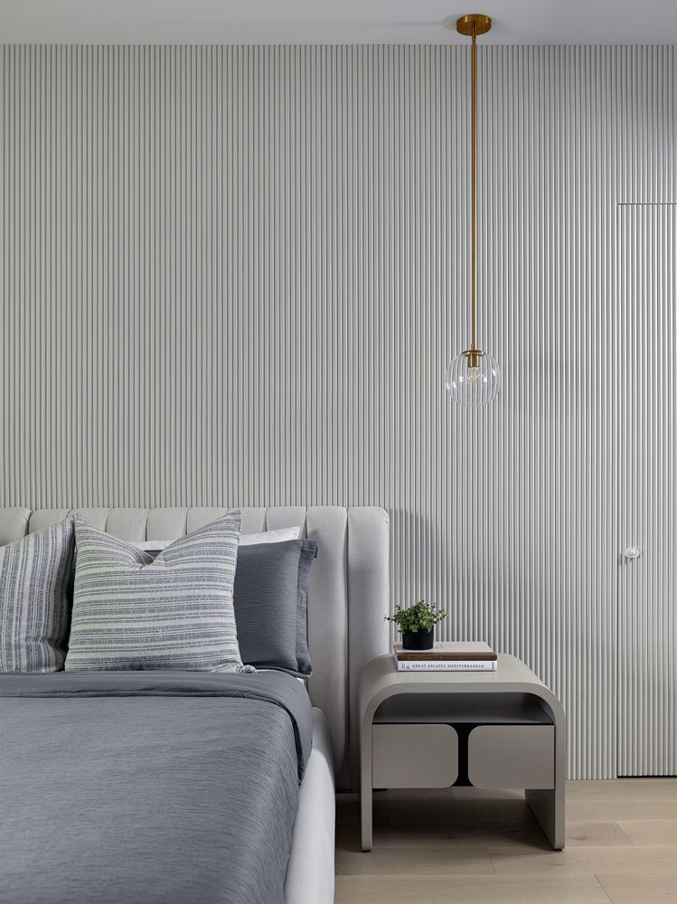 A bedroom with a bed, nightstand, and pendant light in Angelene St by Oakroots Construction