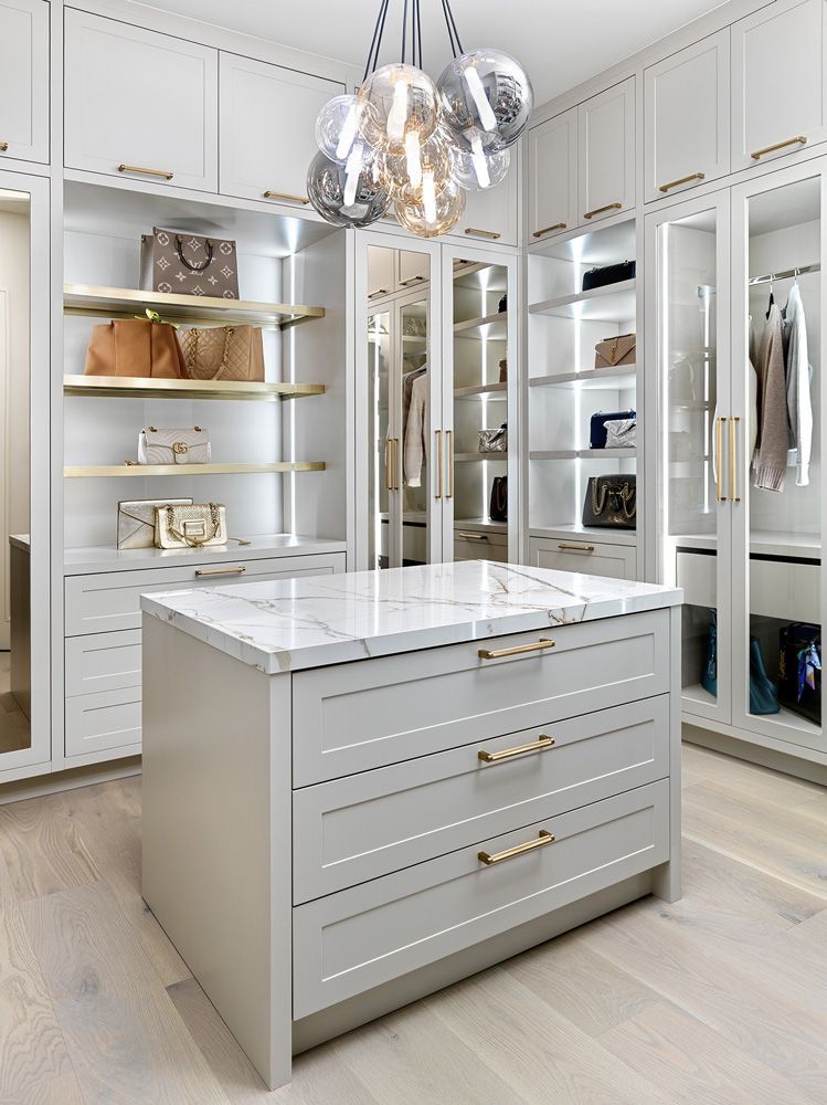A walk in closet with a large island in the middle in Angelene St by Oakroots Construction