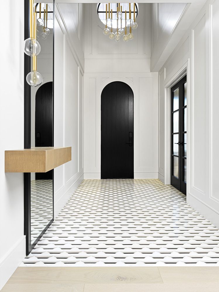 A hallway with a black door and a mirror in Angelene St by Oakroots Construction