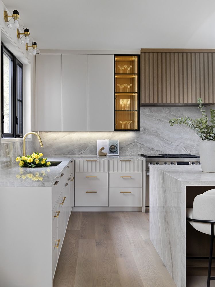 A kitchen with white cabinets, marble counter tops, a sink, and a stove in Angelene St by Oakroots Construction