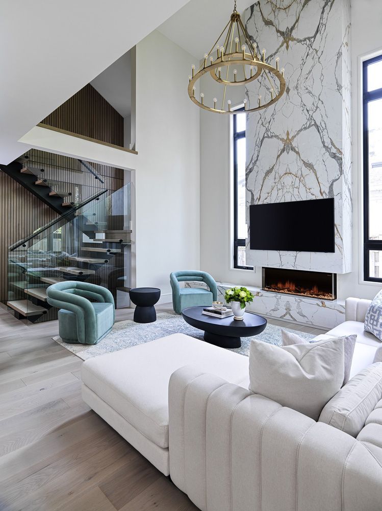 A living room with a couch, chairs, stairs and a fireplace in Angelene St by Oakroots Construction