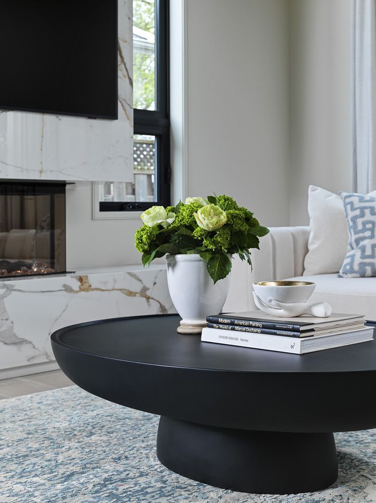 A black coffee table with a vase of flowers on top of it in a living room in Angelene St by Oakroots Construction
