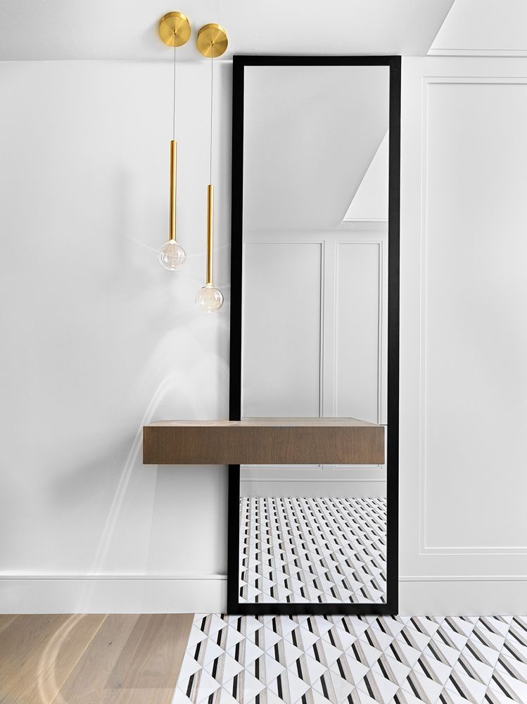 A full-length mirror with a wooden shelf underneath it in a hallway in Angelene St by Oakroots Construction