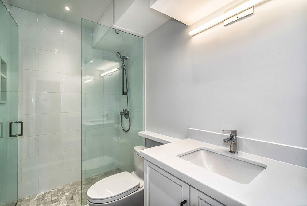 A bathroom with a toilet, sink, and shower in Hazelridge Dr by Oakroots Construction