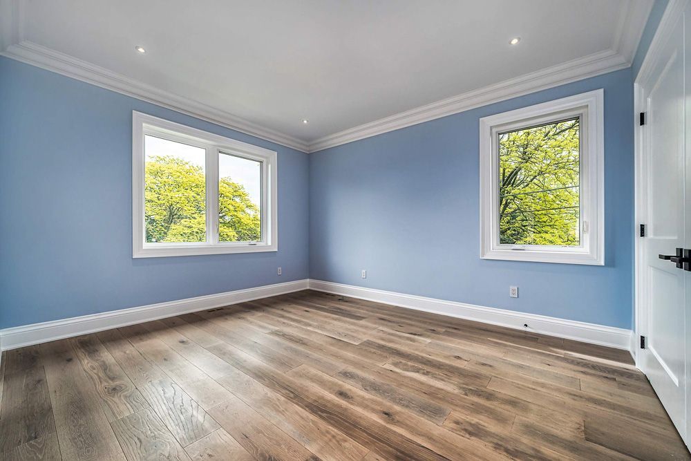 An empty bedroom with blue walls and hardwood floors in Hazelridge Dr by Oakroots Construction