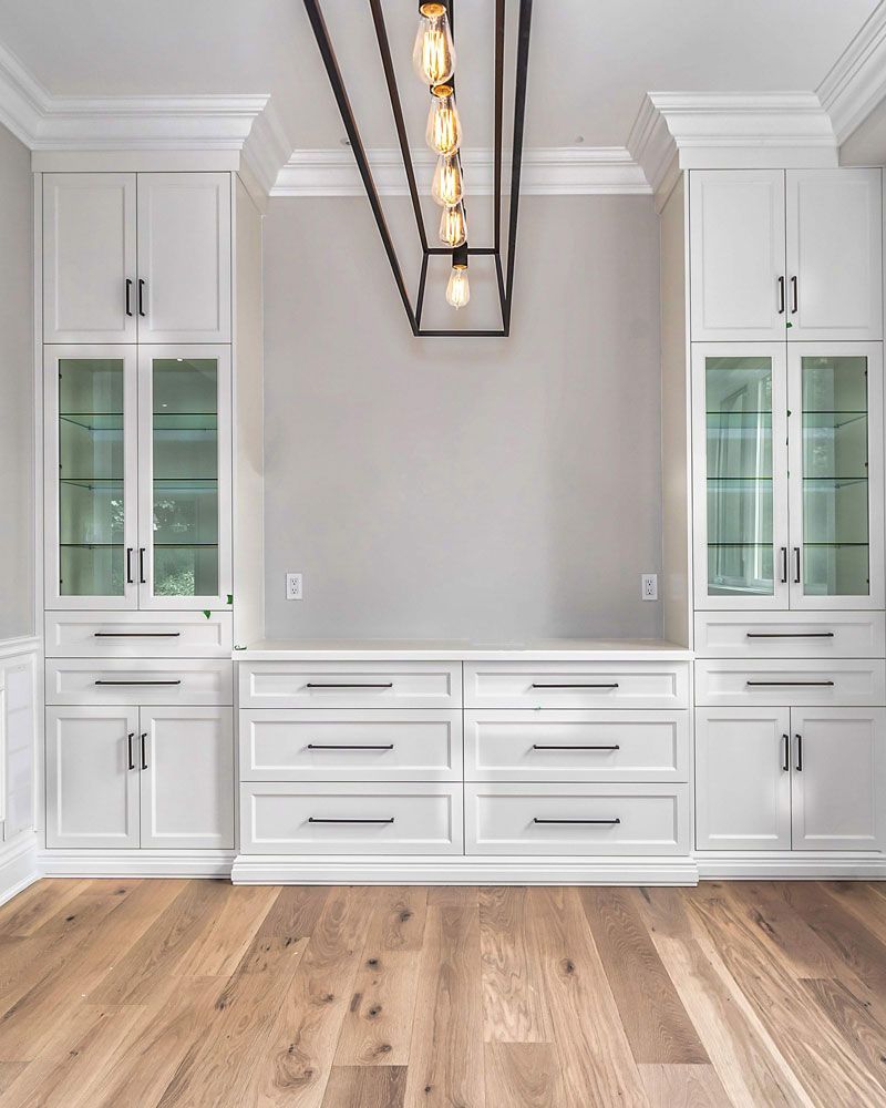 A living room with white cabinets hardwood floors, and a chandelier hanging from the ceiling in Hazelridge Dr by Oakroots Construction
