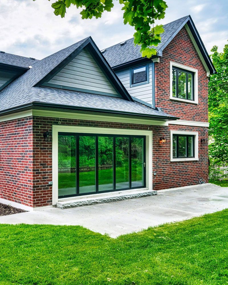 A large brick house with a lot of windows and a patio in front of it in Hazelridge Dr by Oakroots Construction