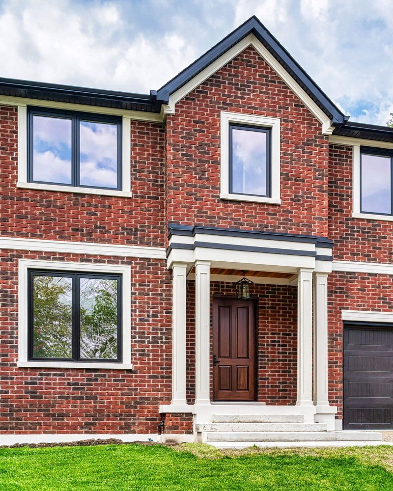 A red brick house with black windows and a black garage door in Hazelridge Dr by Oakroots Construction
