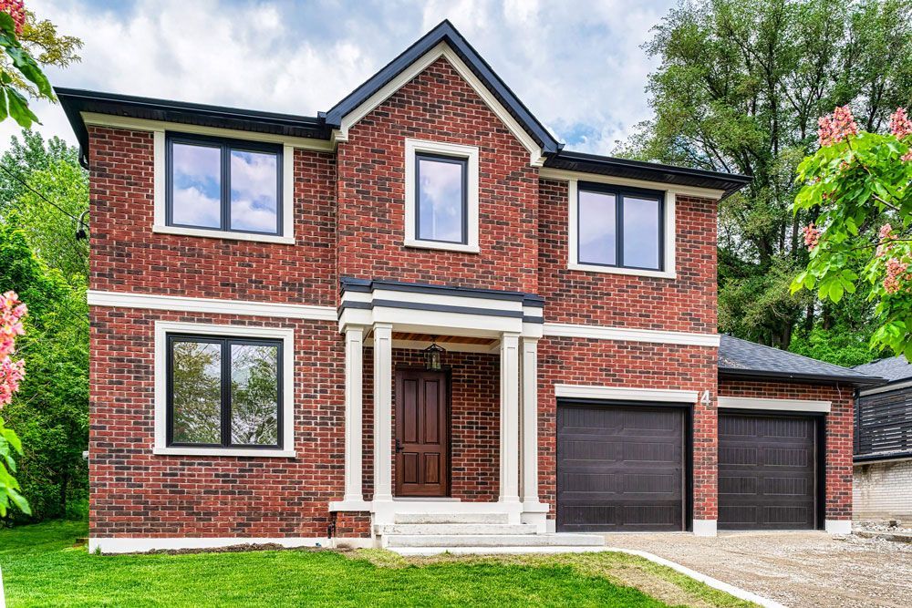 A large red brick house with two garages and a lot of windows in Hazelridge Dr by Oakroots Construction