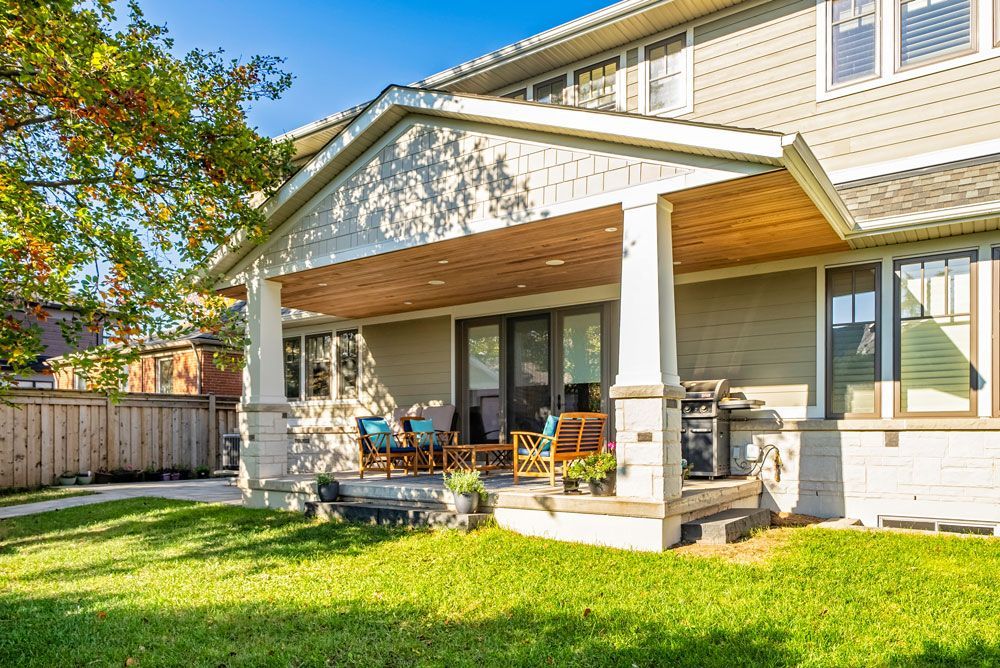 A large house with a large porch and a lush green lawn on Tansley Drive by Oakroots Construction