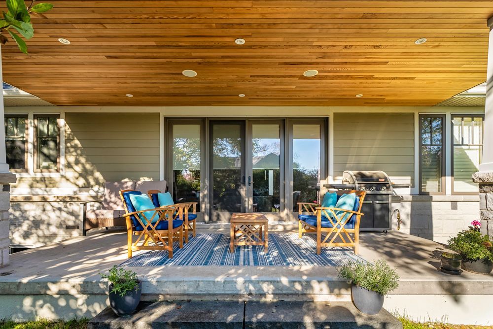 There is a porch with chairs and a table on it on Tansley Drive by Oakroots Construction
