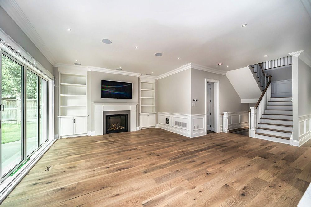 An empty living room with hardwood floors, a fireplace and stairs in Hazelridge Dr by Oakroots Construction